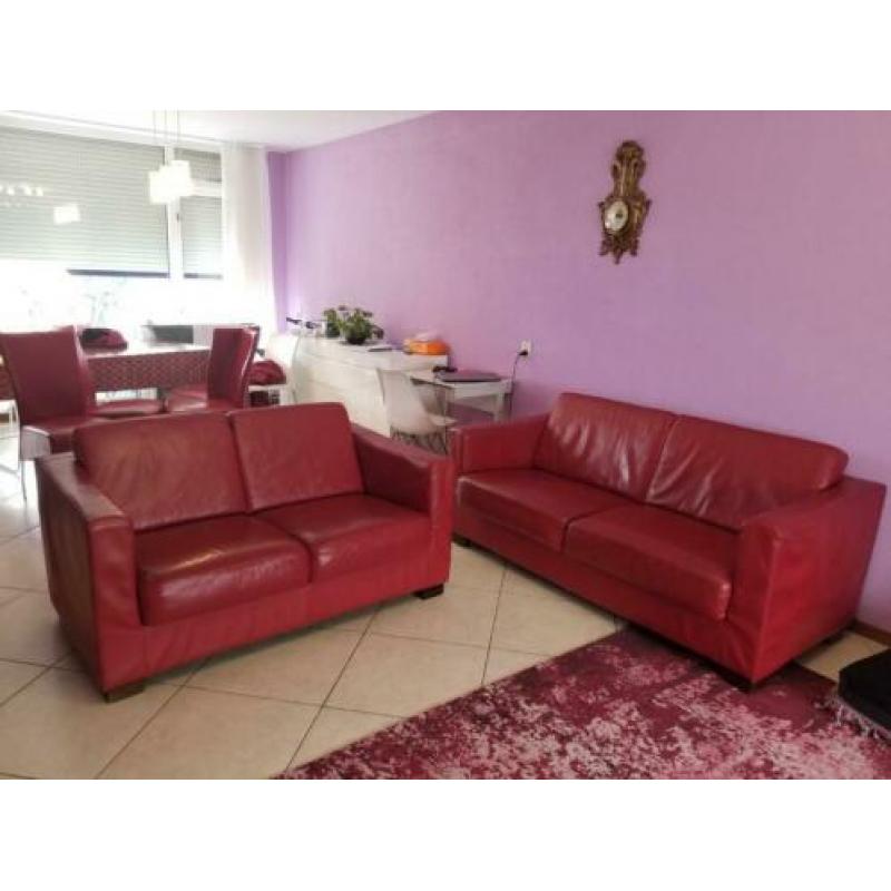 Rode banken met stoelen en grijs tweepersoons slaapbed